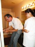 Robert Reid fixes a door knob while Evelyn Figueroa looks on.