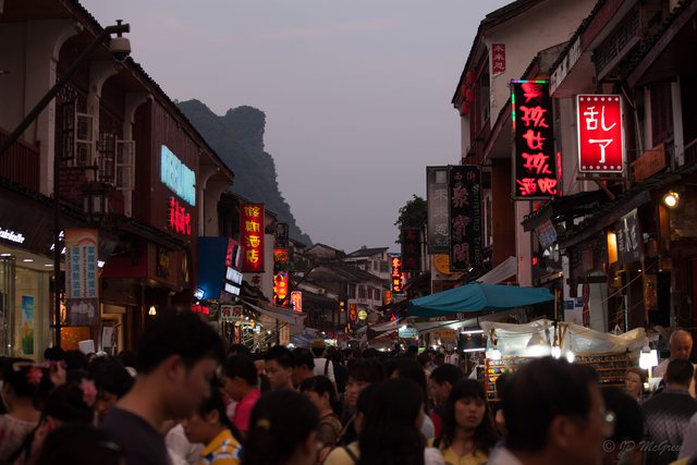 Crowds Fill Street at Dusk in Xingping