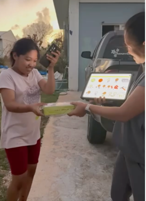 A child receiving their solar power bank outside their home