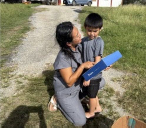 A child receiving their solar power bank outside their home